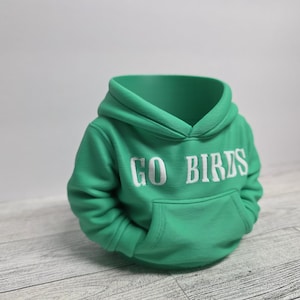 May include: A green hoodie with the words "GO BIRDS" in white block letters across the chest. The hoodie has a front pocket and a hood. The garment is made of a soft material.