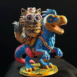 May include: A multi-colored figurine featuring a brown, furry, owl-like creature wearing a white crown and round glasses, riding a blue and orange dinosaur. The dinosaur has a saddle and stands on a circular yellow base with green leaf patterns.