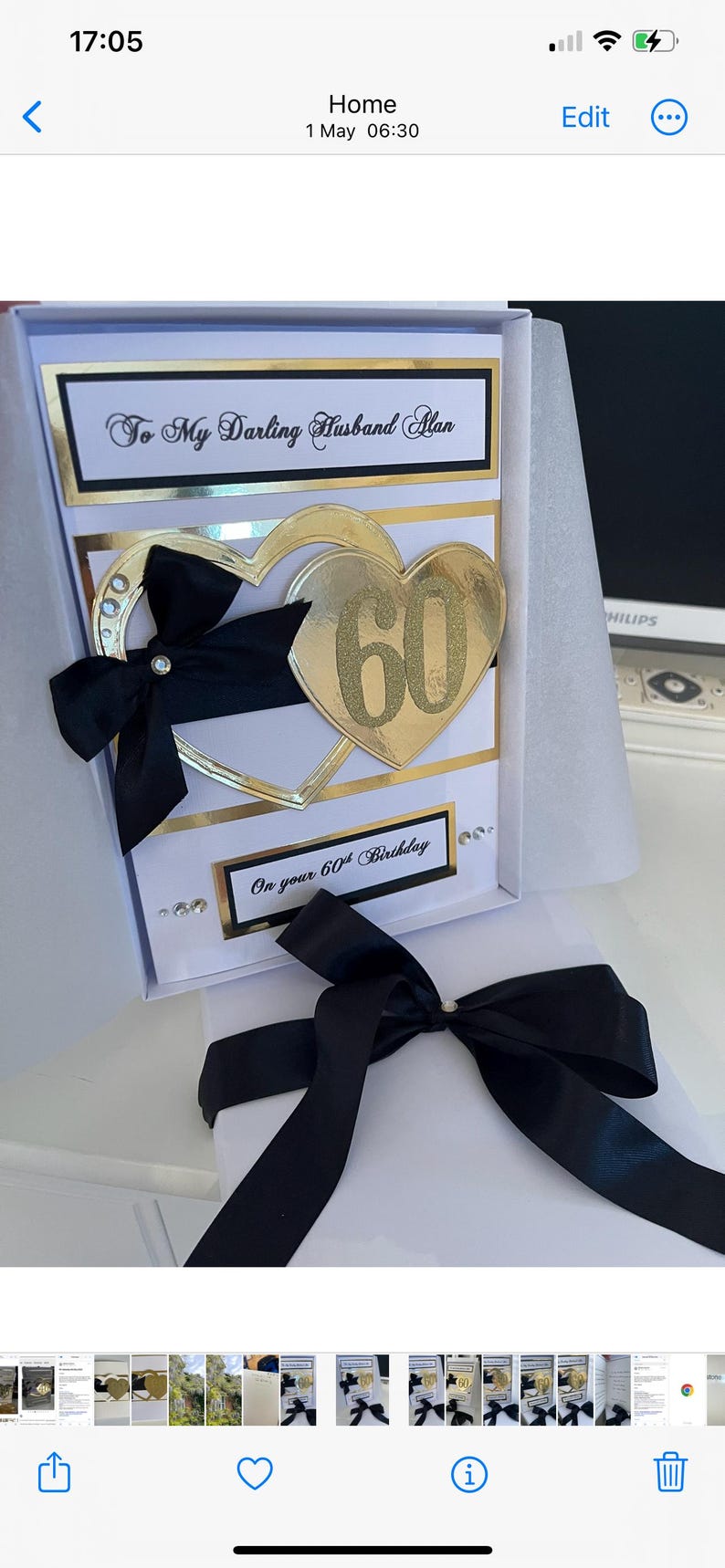 May include: A white card with a black and gold border. The card has a gold heart with the number 60 on it and a black bow. The text on the card reads "To My Darling Husband Alan On your 60th Birthday".