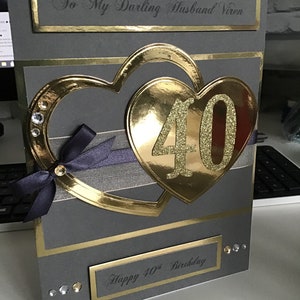 May include: A gray card with gold accents and a large gold heart with the number 40 in glitter. The card says "To My Darling Husband Viren" and "Happy 40th Birthday".