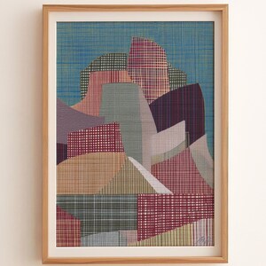 May include: Abstract art print in a wooden frame. The artwork features a colorful geometric design with various shapes and patterns in shades of blue, red, green, and purple. The print has a textured appearance, and the frame is a light brown color.