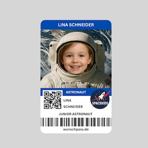Könnte beinhalten: Ein personalisierter Astronautenausweis mit einem lächelnden Kind in einem Raumanzug. Die Karte enthält den Namen "LINA SCHNEIDER", den Titel "JUNIOR ASTRONAUT", einen QR-Code und das "SPACEKIDS"-Logo. Die Website "wunschpass.de" ist unten aufgedruckt.