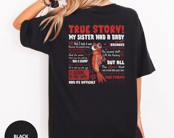 May include: A black t-shirt featuring a graphic on the back with red and white text that reads TRUE STORY! MY SISTER HAD A BABY and a narrative about a shrimp. The design includes a cartoon shrimp illustration, coral accents, and wavy lines.
