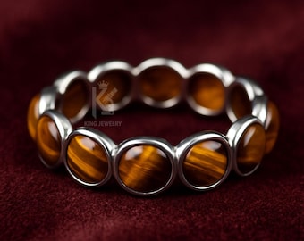 May include: A silver bracelet featuring oval-shaped tiger's eye stones. The stones are a warm brown color with golden stripes, set in individual silver bezels. The bracelet is displayed against a dark red background. The text "KING JEWELRY" is visible.
