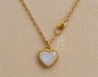 May include: A gold-colored necklace with a heart-shaped pendant. The pendant features a white and blue gemstone set in a gold frame. The chain and clasp are also gold-colored, creating a cohesive and elegant look.