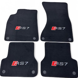 Può includere: Set di quattro tappetini neri per auto. Ogni tappetino presenta il logo "RS7" rosso e bianco. I tappetini sono sagomati per adattarsi ai vani piedi del veicolo e hanno elementi di fissaggio circolari.