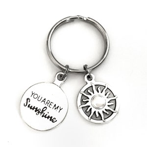 May include: Silver keychain with a round charm that says "You are my sunshine" and a second charm with a sun design.
