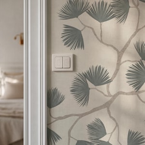 May include: A section of a wall with a light beige wallpaper featuring a repeating pattern of gray pine branches and needles. A white light switch with two buttons is mounted on the wall. A white door frame is visible on the left.