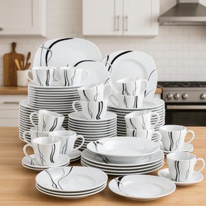 Op de afbeelding: Een complete witte servies set met zwarte en grijze abstracte ontwerpen. De set bevat borden, kommen, kopjes en schotels. De borden en kommen zijn opgestapeld en de kopjes zijn in groepen gerangschikt. Een moderne en elegante serviescollectie.