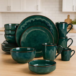 Può includere: Un set completo di stoviglie color teal con piatti, ciotole e tazze. Ogni pezzo ha un bordo marrone scuro. Il set include piatti e ciotole di varie dimensioni, insieme a diverse tazze, il tutto disposto su una superficie di legno.