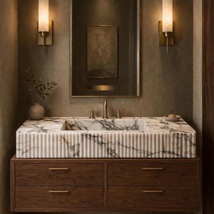May include: A wall-mounted bathroom vanity featuring a fluted white marble countertop with grey veining, a rectangular integrated sink, and a dark wood cabinet with four drawers accented by thin, horizontal brass-toned metal handles.