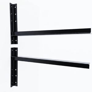 May include: Two black L-shaped metal shelf brackets, each featuring a vertical mounting plate with four pre-drilled circular holes and a long horizontal support arm extending outward to hold a shelf securely in place against a wall surface.