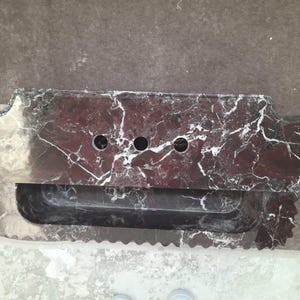 May include: A rectangular, dark red marble sink with white veining. The sink has three circular faucet holes and a built-in, rectangular basin. The edges are scalloped and the overall design is modern.