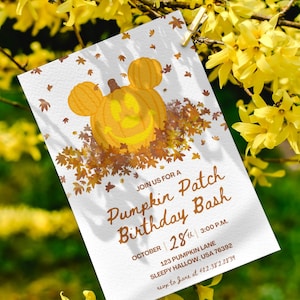 Könnte beinhalten: Eine weiße Einladungskarte für eine Pumpkin Patch Birthday Bash, mit einem lächelnden Kürbis-Design mit Mickey Mouse Ohren. Die Karte enthält Datum, Uhrzeit und Ort, mit einem Hintergrund aus gelben Blumen.