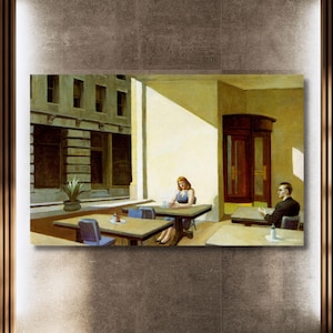 Puede incluir: Una impresión enmarcada de la pintura "Nighthawks" de Edward Hopper. La obra representa una escena de restaurante con tres personas sentadas en mesas. La paleta de colores incluye tonos de amarillo, marrón y azul, creando una sensación de aislamiento y realismo urbano.