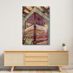 May include: A framed print of a fairytale illustration. The artwork shows a bed with many mattresses, topped with a canopy. A person is lying in the bed. The color palette includes shades of pink, blue, and brown.