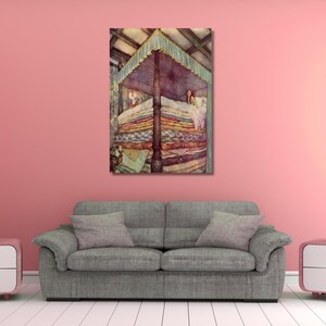 May include: A framed print of a fairytale illustration. The artwork shows a four-poster bed piled high with colourful bedding. A woman is seated in the bed under a canopy. The artwork is set against a backdrop of a pink wall and a grey sofa.