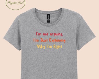 Puede incluir: Camiseta gris con la frase "I'm not arguing, I'm Just Explaining Why I'm Right" en naranja, rojo y amarillo. La camiseta tiene cuello redondo y mangas cortas.