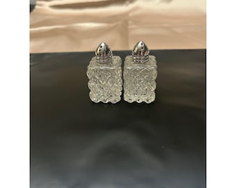 Salero y pimentero vintage de vidrio prensado transparente con punta de diamante y tapas cromadas.