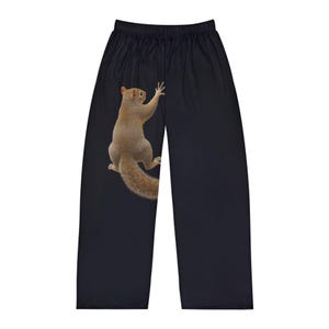 Op de afbeelding: Zwarte pyjamabroek met een gedetailleerde illustratie van een eekhoorn. De eekhoorn is afgebeeld in bruin- en beigetinten, met uitgestrekte armen. De broek heeft een tailleband met trekkoord.
