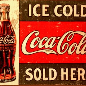 Könnte beinhalten: Vintage-Schild aus Metall, das für Coca-Cola wirbt. Das Schild hat einen roten Hintergrund mit dem Coca-Cola-Logo in Weiß. Der Text "ICE COLD" befindet sich über dem Logo und "SOLD HERE" darunter. Auf der linken Seite des Schildes ist eine Flasche Coca-Cola abgebildet.