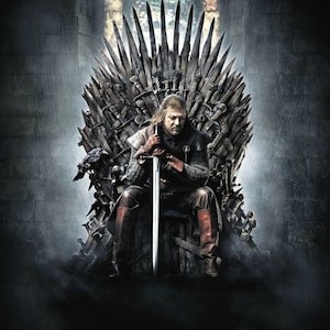 May include: A man sits on a large, ornate iron throne with a sword in his hand. The throne is decorated with swords and other weapons.