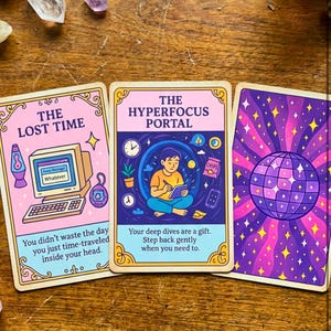 Puede incluir: Tres cartas de tarot con fondos rosa pastel y morado. Las cartas presentan ilustraciones de una computadora retro, una persona escribiendo y una bola de discoteca. El texto en las cartas incluye "The Lost Time" y "The Hyperfocus Portal."