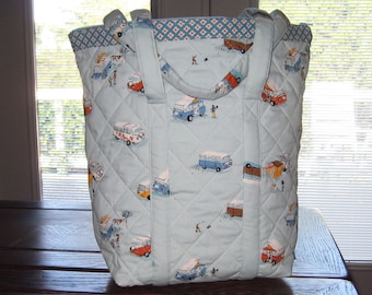 May include: A light blue quilted tote bag with a white and orange patterned design featuring vintage vans. The bag has two long handles and a zipper closure.