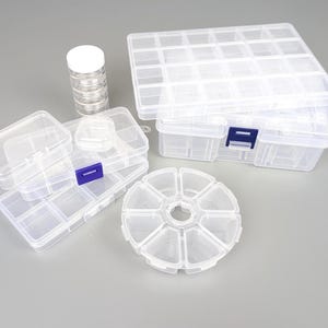 Può includere: Una collezione di contenitori di stoccaggio in plastica trasparente di varie dimensioni. I contenitori includono scatole rettangolari con più scomparti, un contenitore rotondo con sezioni segmentate e piccoli barattoli cilindrici. Per organizzare piccoli oggetti.