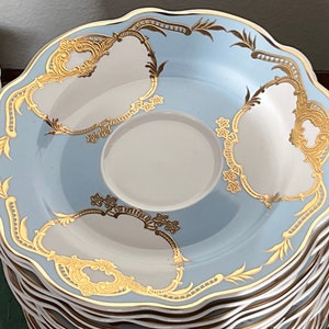 K&ouml;nnte beinhalten: Ein Stapel blauer und wei&szlig;er Porzellansaucers mit goldenen Verzierungen und filigranen Blumendesigns. Die Untertassen haben einen gewellten Rand und eignen sich perfekt zum Servieren von Tee oder Kaffee.