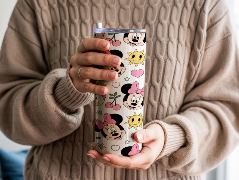 Pu&ograve; includere: Un bicchiere cilindrico con sfondo color crema caratterizzato da un motivo ripetuto di volti di Minnie, fiocchi rosa, soli gialli, ciliegie rosse, cuori rosa e piccole stelle bianche. Il bicchiere include un coperchio trasparente e una cannuccia bianca.