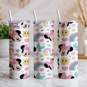 Pu&ograve; includere: Tre bicchieri cilindrici bianchi con coperchi trasparenti e cannucce bianche, ciascuno caratterizzato da un motivo ripetuto di volti di Minnie con fiocchi rosa, soli gialli, cuori rosa, arcobaleni blu, piccoli fiori bianchi e farfalle azzurre.