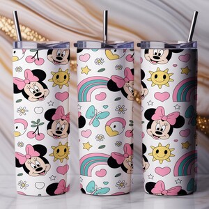 Pu&ograve; includere: Tre bicchieri cilindrici con coperchi e cannucce in metallo, caratterizzati da uno sfondo bianco con un motivo ripetuto di volti di Minnie, soli gialli, cuori rosa, farfalle blu, arcobaleni, ciliegie e piccoli fiori bianchi.