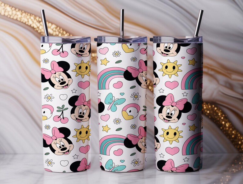 Pu&ograve; includere: Tre bicchieri cilindrici con coperchi e cannucce in metallo, caratterizzati da uno sfondo bianco con un motivo ripetuto di volti di Minnie, soli gialli, cuori rosa, farfalle blu, arcobaleni, ciliegie e piccoli fiori bianchi.
