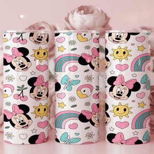 Pu&ograve; includere: Tre bicchieri cilindrici con un motivo ripetuto su sfondo bianco. Il design include volti di Minnie con fiocchi rosa, soli gialli sorridenti, cuori rosa, farfalle blu, arcobaleni e piccoli fiori bianchi.