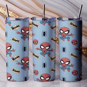 May include: Three stainless steel tumblers with lids and straws. Each tumbler features a light blue background with a repeating pattern of Spider-Man illustrations, spider webs, and the word "BOOM!" in yellow speech bubbles.