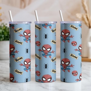 May include: Three cylindrical tumblers with a light blue background, featuring a repeating pattern of Spider-Man illustrations, spider icons, and "BOOM!" speech bubbles. Each tumbler has a white straw.