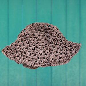 May include: A crocheted sun hat in a muted brown color. The hat features a wide, slightly wavy brim and an open, airy stitch pattern. The hat is designed to provide shade and is suitable for outdoor wear.