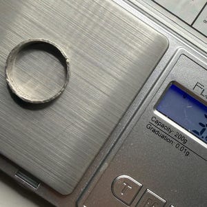 May include: A silver-toned metal ring with a textured, uneven surface resting on a digital scale. The scale display shows a weight of 3.25 grams. The scale is a Fuzion brand model with a 200-gram capacity and 0.01-gram graduation increments.