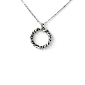 May include: A silver-toned necklace with a twisted rope design pendant. The pendant is a circular shape, suspended from a delicate chain. The jewelry is set against a white background.