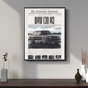 May include: Framed print featuring a vintage BMW E30 M3 car. The print is designed to look like a newspaper clipping, with the headline "The Autobahn Chronicle" and the car's model name prominently displayed. The image is in black and white.