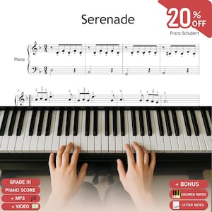 Puede incluir: Un teclado de piano con teclas blancas y negras situado bajo una partitura musical titulada Serenade de Franz Schubert. La partitura muestra notas en un pentagrama con numeración de dedos. Etiquetas rojas indican la partitura de nivel Grade III.
