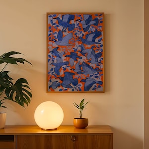 Op de afbeelding: Een rechthoekig ingelijst kunstwerk aan de muur met een herhalend patroon van blauwe vogels in vlucht tegen een levendige oranje achtergrond met gestileerd gebladerte. Het kunstwerk zit in een dunne houten lijst aan de muur.