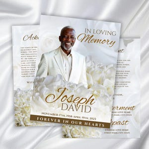 Könnte beinhalten: Eine Gedenkkarte mit einem Foto eines lächelnden Mannes in einem weißen Anzug, umgeben von weißen Rosen. Die Karte trägt die Aufschrift "In Loving Memory" und enthält den Namen "Joseph David" sowie die Daten "17. November 1958 - 19. April 2023."