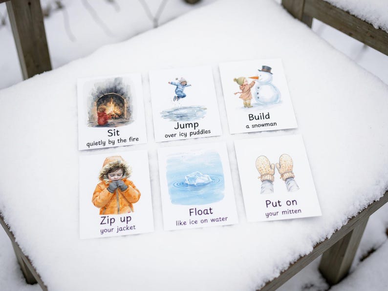 Puede incluir: Seis tarjetas ilustradas con actividades de invierno: sentarse junto al fuego, saltar sobre charcos helados, construir un mu&ntilde;eco de nieve, subir la cremallera de la chaqueta, flotar sobre el hielo y ponerse los guantes. Las tarjetas est&aacute;n sobre una superficie de madera nevada.
