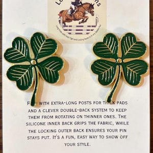 May include: Two green and gold shamrock pins. Each pin features a four-leaf clover design with gold trim. The pins are displayed on a white card with the text "Long Spot Pins" and a logo of a horse jumping over a fence.