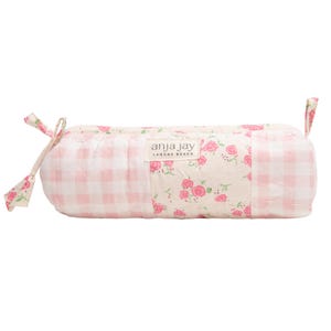 May include: A cylindrical, quilted pencil case with a pink and white gingham pattern and floral accents. The center panel features a floral print with pink roses. The brand name "anja jay LAGUNA BEACH" is printed on a label.