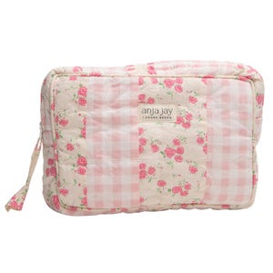 May include: A rectangular, quilted cosmetic bag with a patchwork design. The bag features a combination of pink gingham and floral fabric with pink roses on a cream background. The brand name "anja jay" is visible on the front.