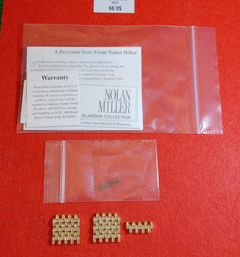 May include: A collection of Nolan Miller Glamour Collection jewelry pieces, including two square-shaped earrings and a smaller rectangular piece, all in a gold tone with embedded rhinestones. The image also shows a small bag of pins and a warranty card.