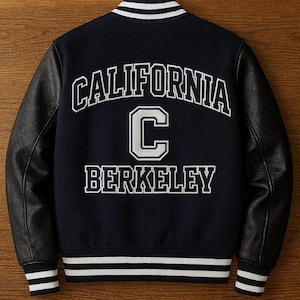 Könnte beinhalten: Marineblaue Collegejacke mit schwarzen Lederärmeln. Auf der Rückseite stehen die Worte "CALIFORNIA" über einem großen weißen "C" und das Wort "BERKELEY" in weißen Blockbuchstaben. Kragen, Manschetten und Saum haben weiße Streifen.